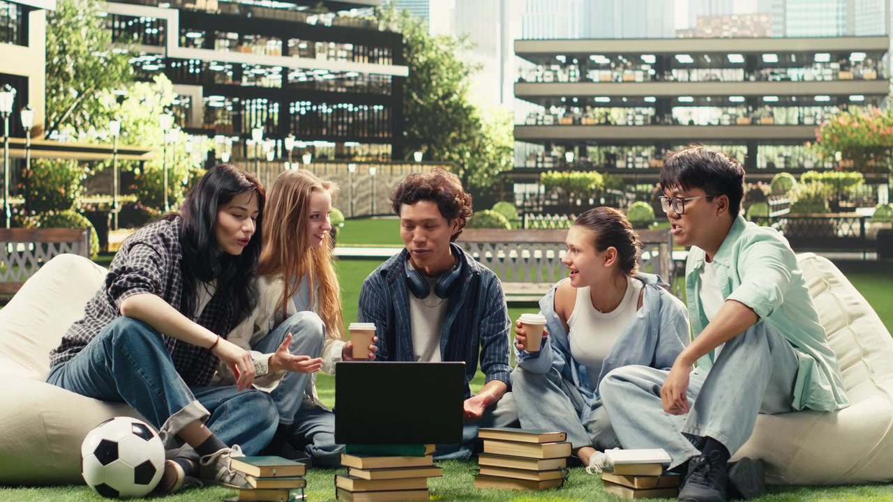 Diverse peers gathering on campus grass for group study session