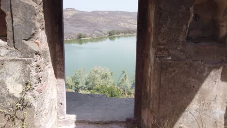 Push-Through-Archway-of-Ancient-Ranthambore-Fort-to-Reveal-Rajbagh-Lake-at-Ranthambore-National-Park,-Rajasthan,-India