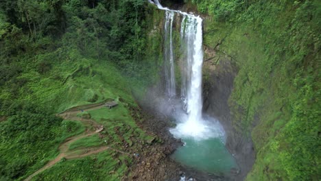 aerial rising on eco chontales waterfall and natural turquoise pond surrounded by dense green rain forest, costa rica