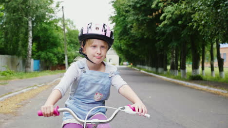 a blonde girl in a helmet riding a bike on the street 1