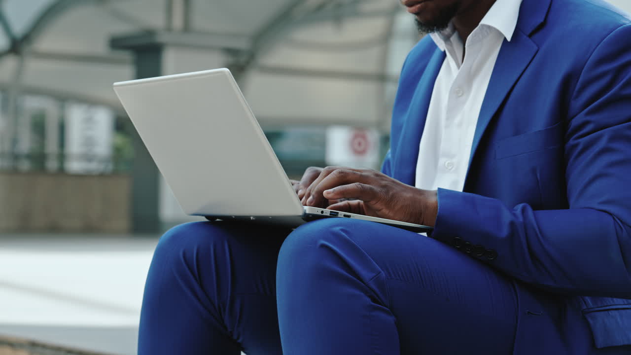 Man in blue suit using a laptop outdoors