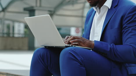 man in blue suit using a laptop outdoors