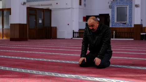 old man turning his head during prayer in mosque