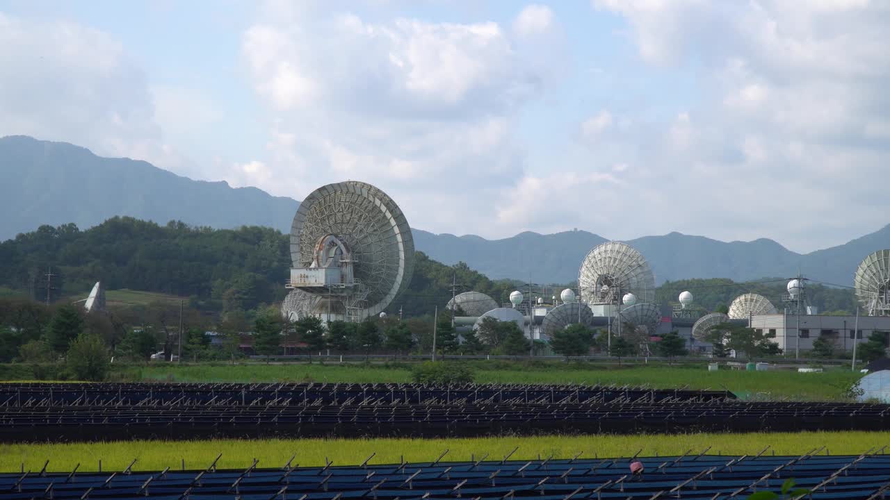 낮에 한국 금산에 있는 kt sat 위성 센터 - 논과 인삼밭을 통해 접시를 향해 줌인 샷