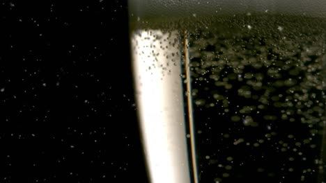 animation of confetti falling and bubbles rising in glass of champagne on black background