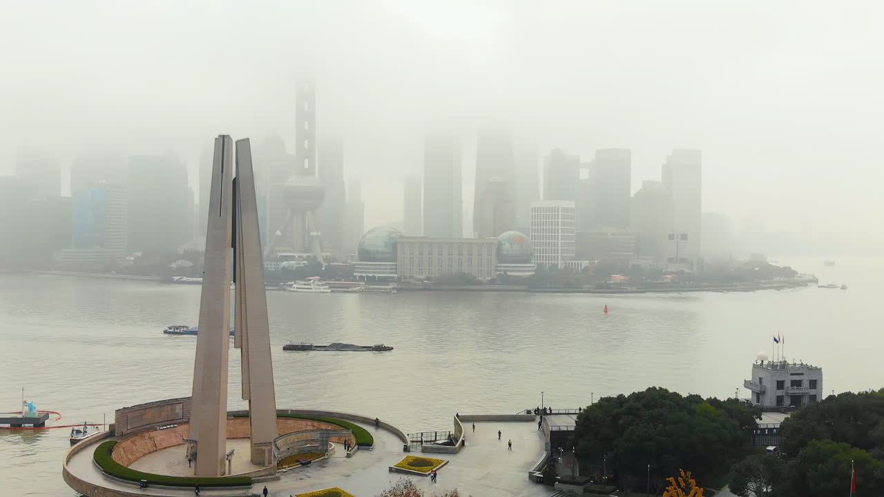vista clara del monumento a los héroes del pueblo frente a un paisaje urbano nebuloso de shanghai