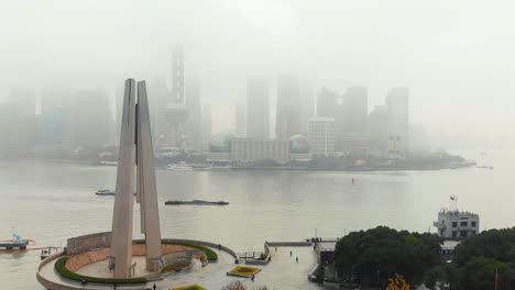 clear view of the monument to the people's heroes in front of a foggy shanghai cityscape