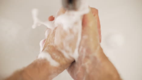 caucasian man washes hands with water, high angle close up slow motion