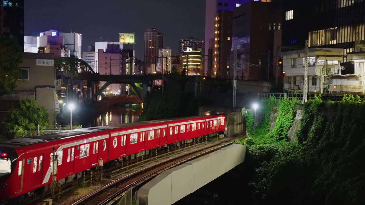 Treno rosso che arriva alla stazione di Ochanomizu ad Akihabara, Giappone, vista notturna