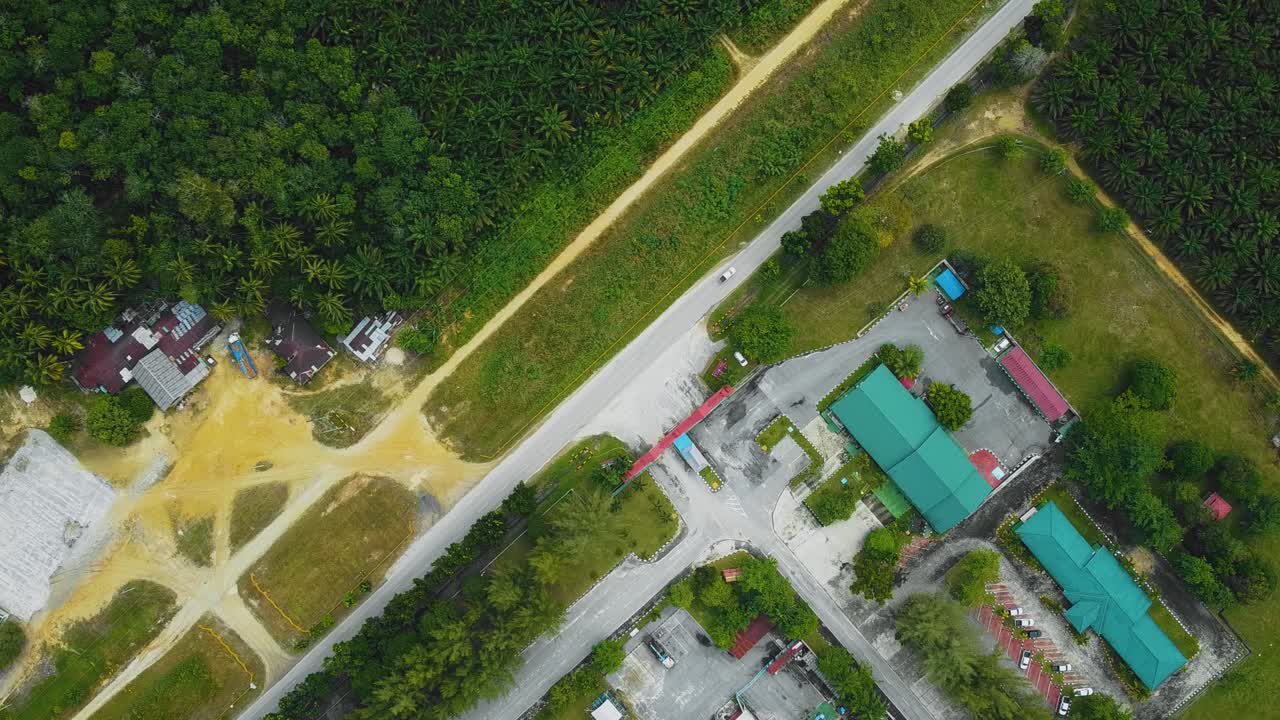 야자유 공장 폐수 거주지의 영화적 드론 영상은 인도네시아에 있는 야자나무 삼림 벌채로 둘러싸인 건물, 주택, 주요 도로 및 인프라로 구성되어 있습니다.