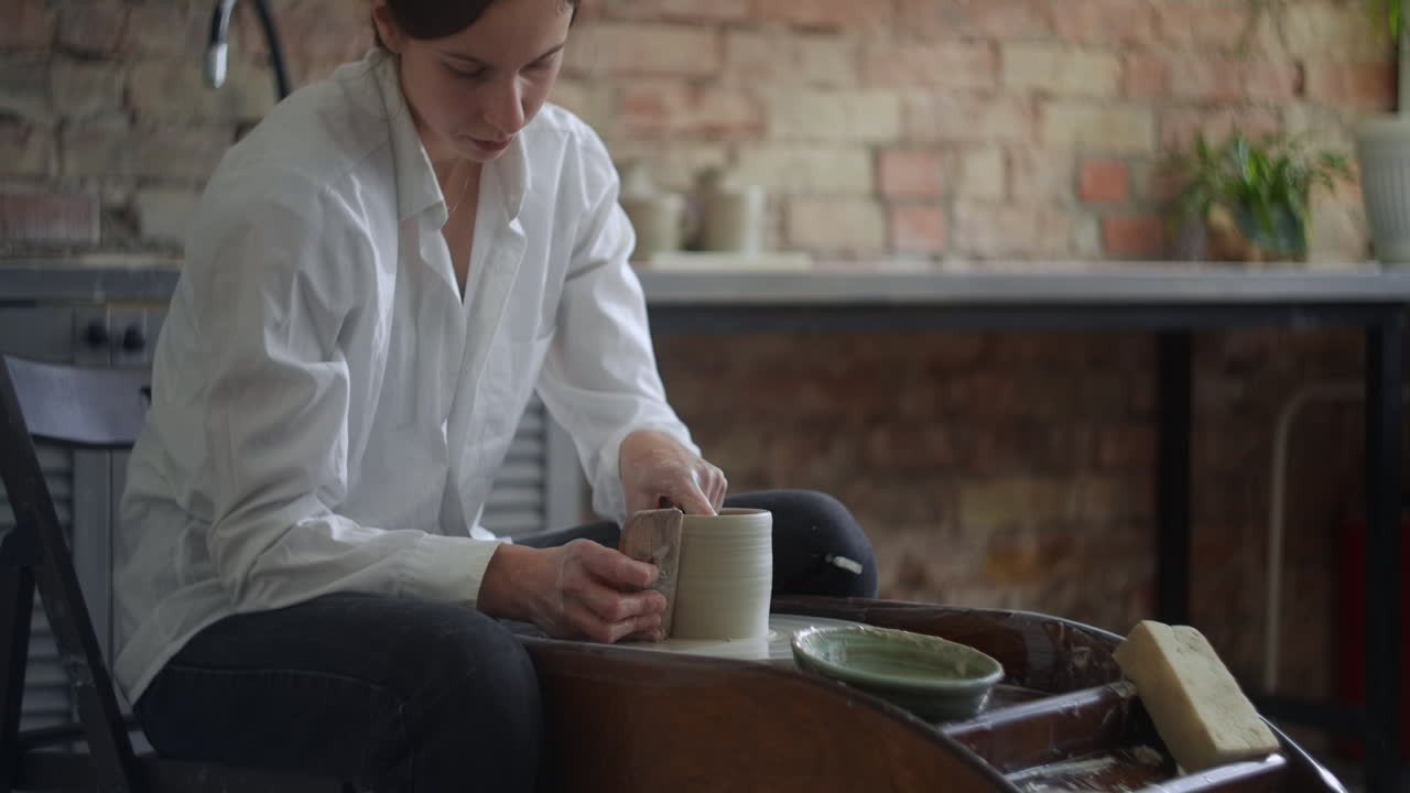Woman making a ceramic mug on a pottery wheel