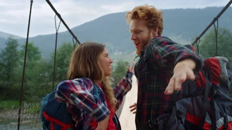 two travelers dance together on river bridge. excited couple enjoy mountain hike