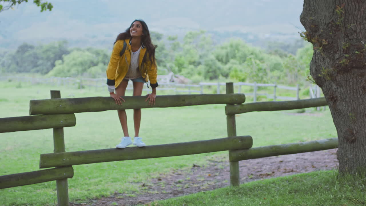 Young woman, backpack and countryside fence