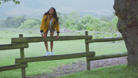 Young-woman,-backpack-and-countryside-fence