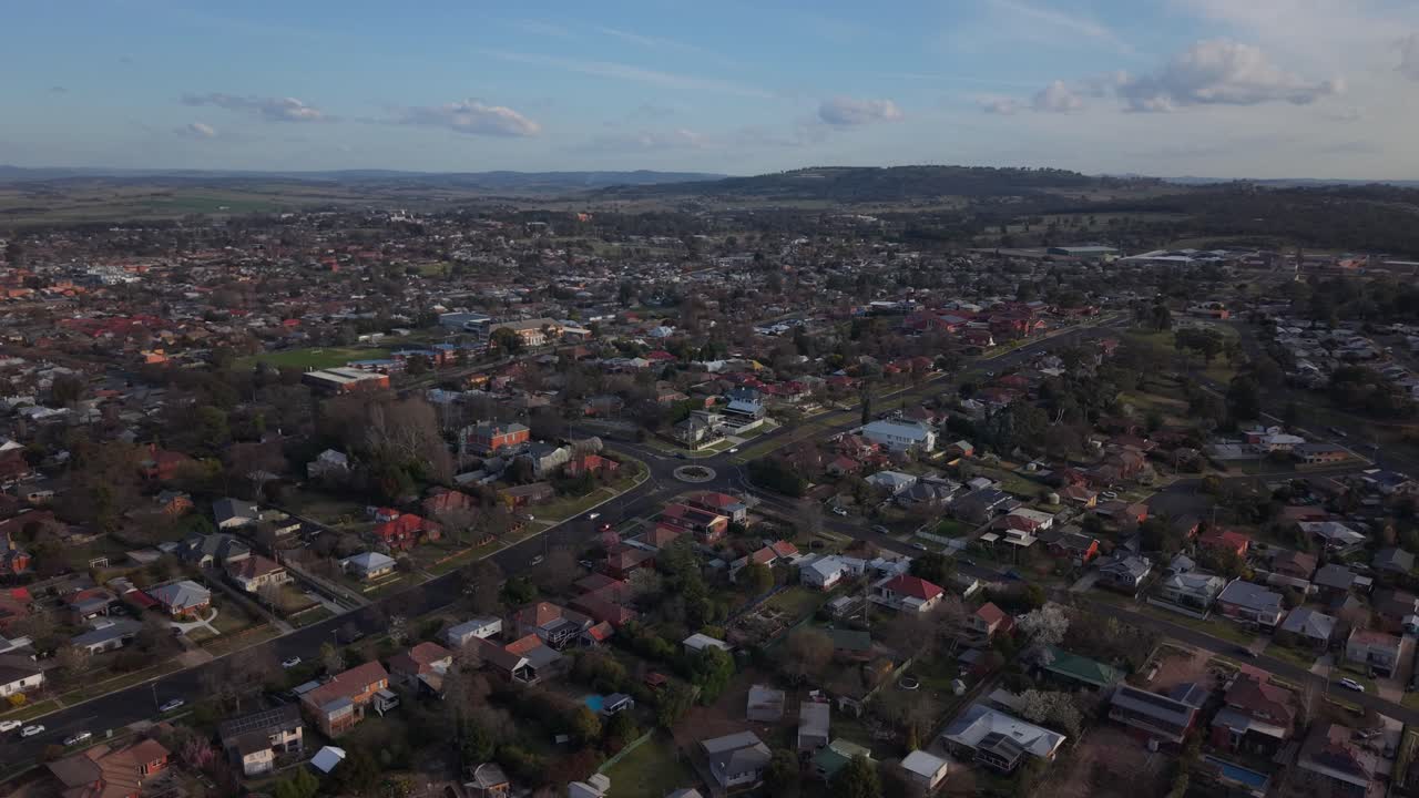 Suburban streets as sunset casts golden tones across neighborhood, panoramic aerial establishing of Bathurst NSW Australia