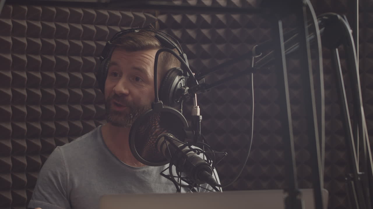 feliz locutor de radio con barba habla con el micrófono en un estudio de radio