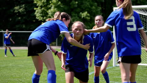 youth female soccer team showing support and helping a teammate on the field
