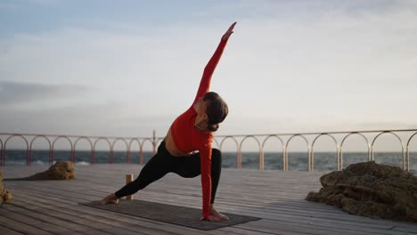 woman practicing yoga on a pier overlooking the sea