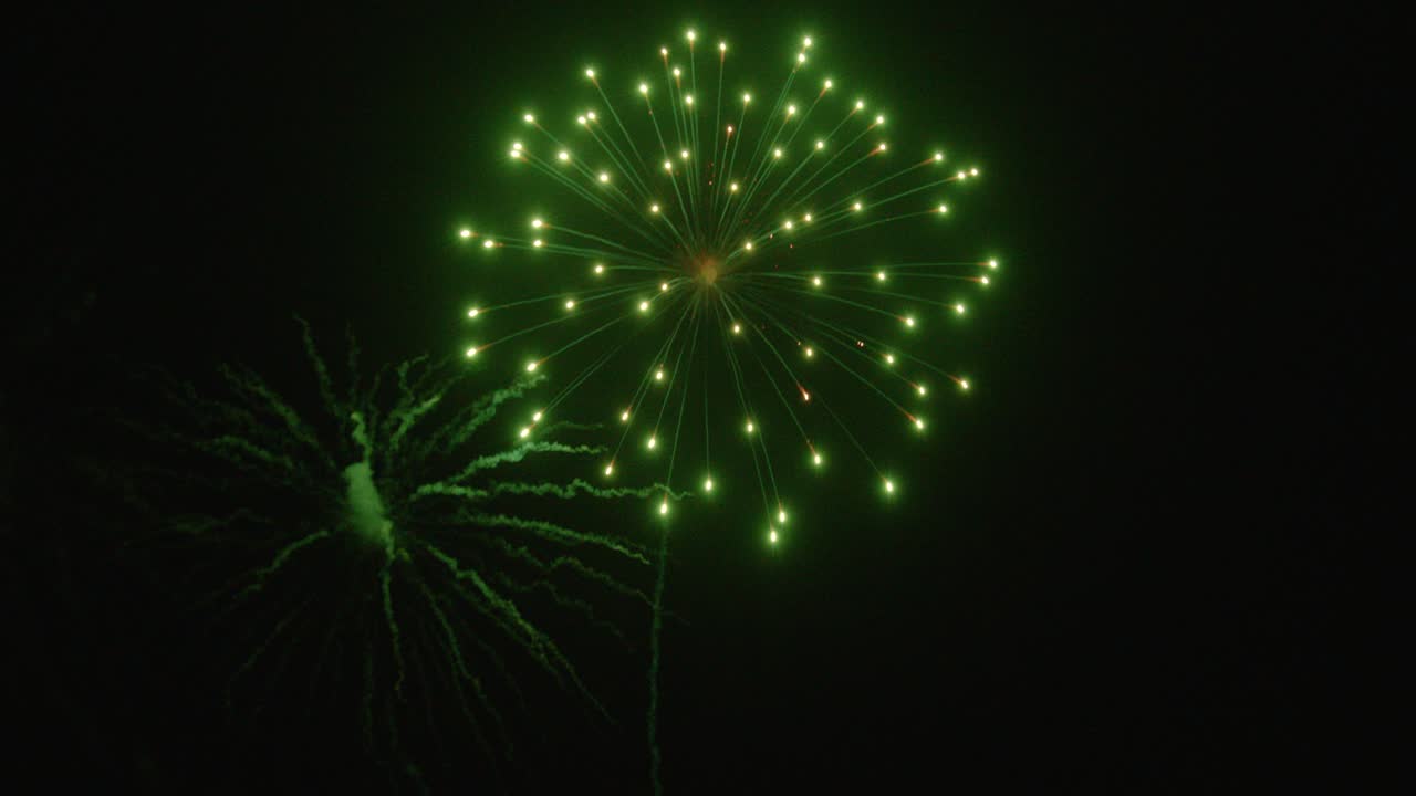 Single slow motion firework rocket trailing into the sky then exploding to cover the night sky