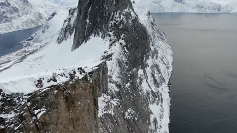 drone view in tromso area in winter flying over a snowy mountain showing segla rocky peak in segla, norway