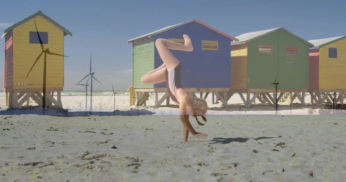 Menina transferindo o peso e chutando a perna para fazer uma roda na areia, perto de cabanas coloridas, praticando esportes