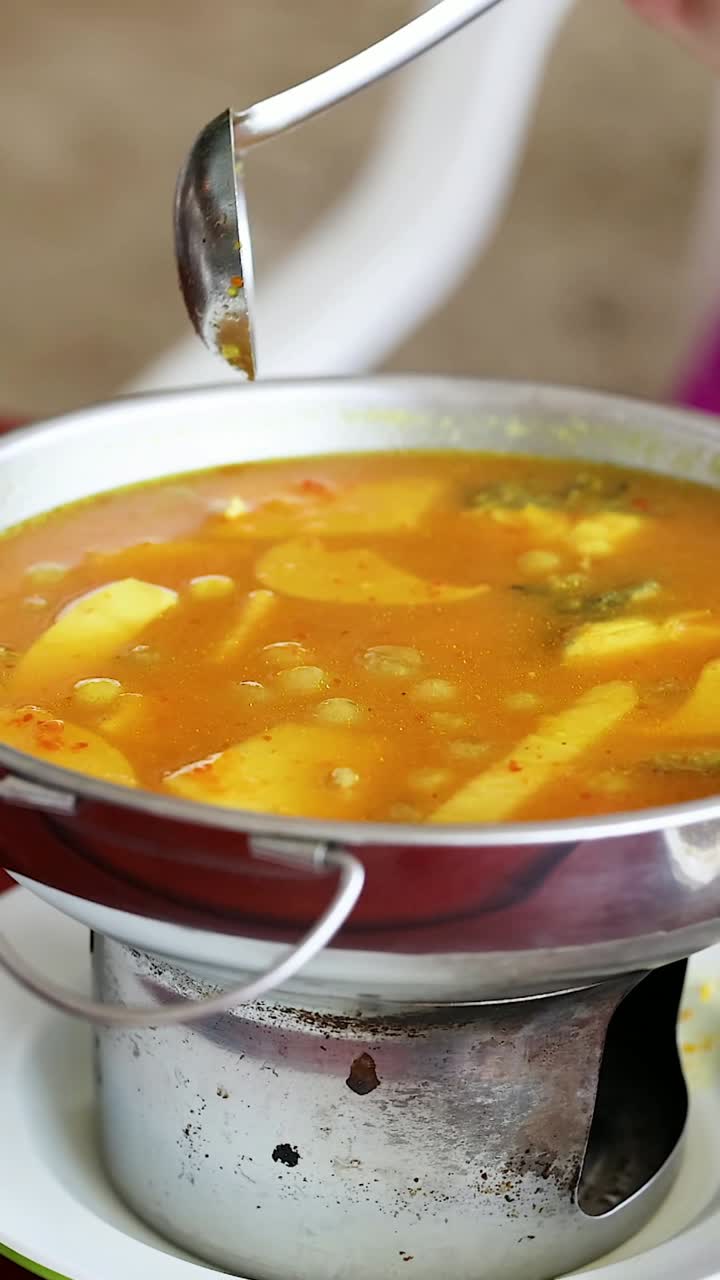 persona que sirve curry amarillo en una mesa