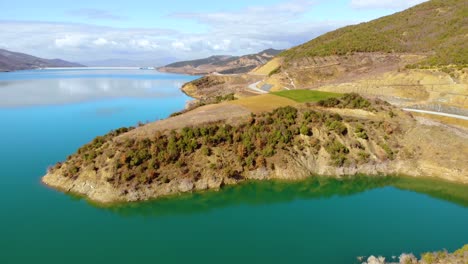 superficie azul turquesa de aguas tranquilas del lago de montaña rodeado de laderas con parcelas verdes a lo largo de la carretera panorámica