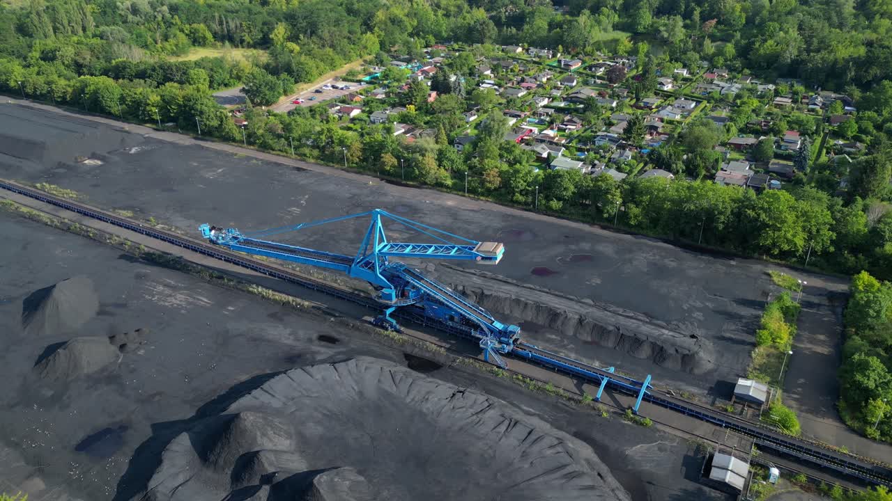 Spreader reclaiming coal Excavator at a coal terminal near residential area. Gorgeous aerial view flight wide orbit overview drone