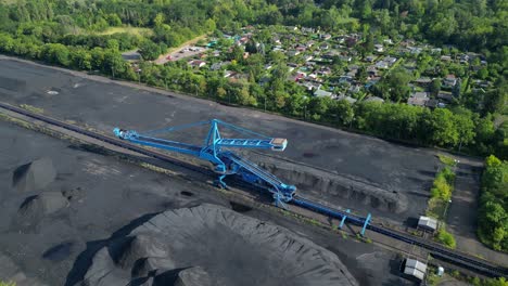 spreader reclaiming coal excavator at a coal terminal near residential area. gorgeous aerial view flight wide orbit overview drone