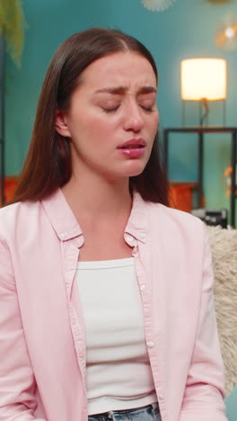young woman frowning at smartphone after contest loss shows sad reaction and very strong frustration