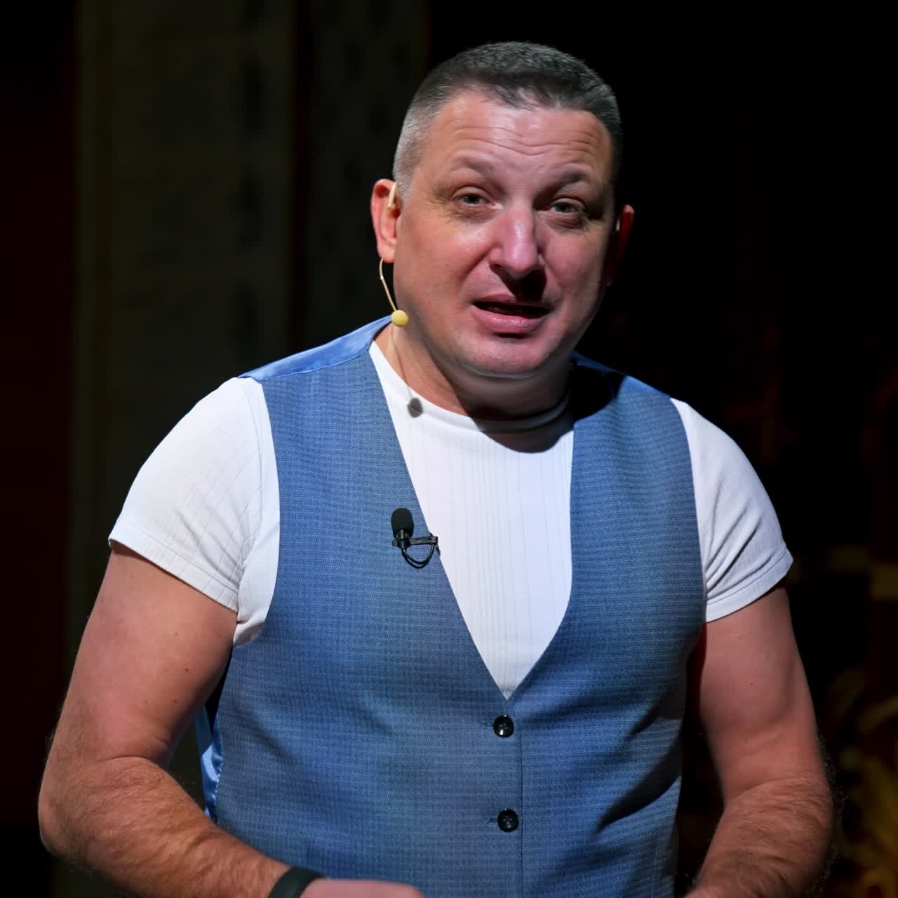 Performer announces future theater season. Actor is sitting in empty theater on red velvet chair with sheet of paper in hands