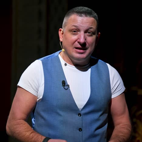 performer announces future theater season. actor is sitting in empty theater on red velvet chair with sheet of paper in hands