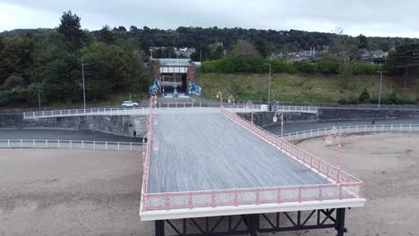 colwyn bay welsh seaside town pier boardwalk aerial view over moody overcast sandy low tide beach pull away