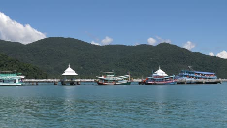 Slow-motion-panning-shot-of-a-long-pier-with-many-colorful-boats-on-the-island-of-Koh-Kood,-Thailand