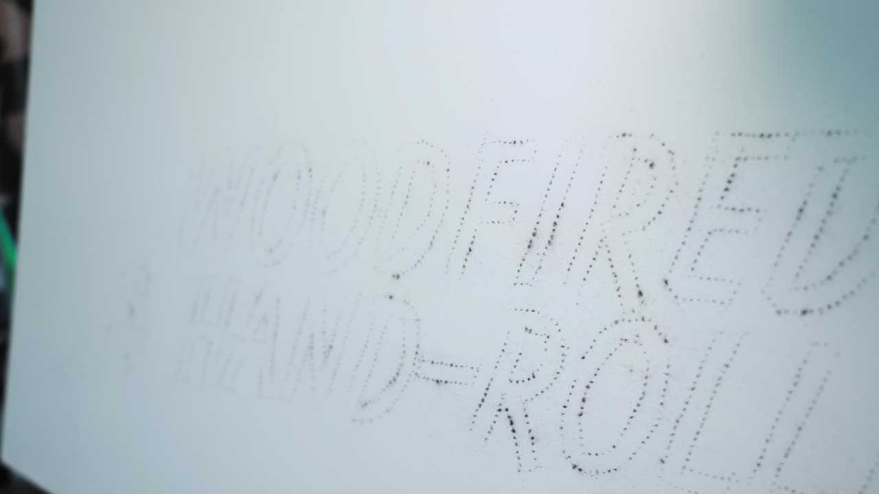 Close-up of charcoal dust pouncing technique used to transfer patterns onto a surface, showing traditional marking method, fine detail, and artistic preparation process
