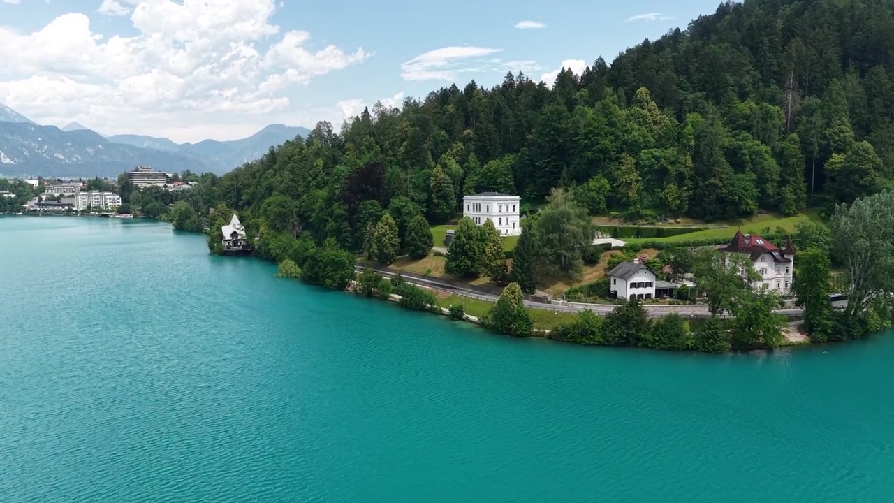 Lago di Bled, Slovenia. Ripresa drone di strada costiera e case sopra l'acqua alpina turchese.