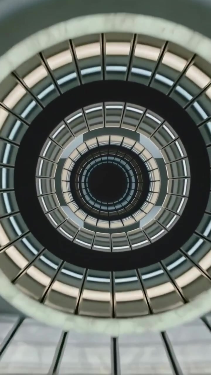 Video verticale: Telecamera che si muove lungo l'atrio, mostrando balconate circolari, griglia e luci verso il centro.