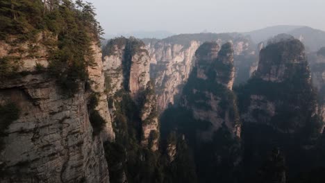forward-moving aerial shot gliding past sheer sandstone cliffs and forested ravines in zhangjiajie national park's iconic terrain