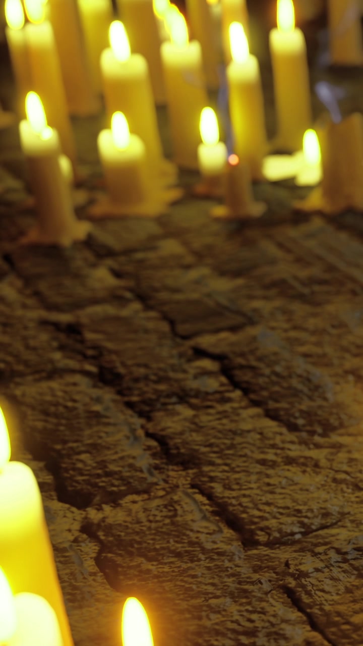 Candles are lit on a stone surface during a gathering at night