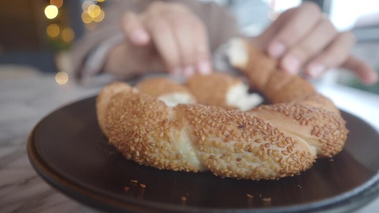 Hands Breaking a Traditional Turkish Simit Bagel