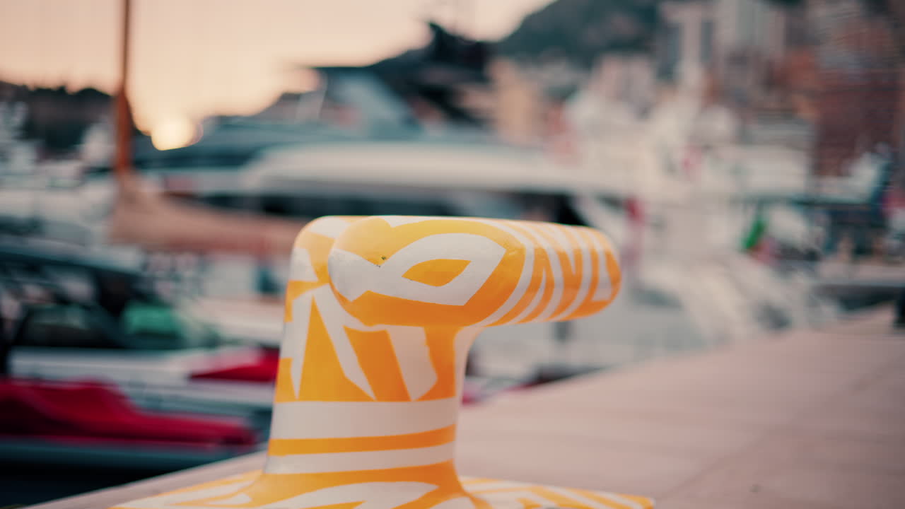 Close up of a white and yellow dock cleat in a harbour with boats on the background