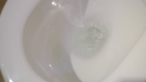 slow motion mid shot of a toilet flushing water