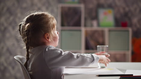 pretty little child takes break in drawing and drinks water