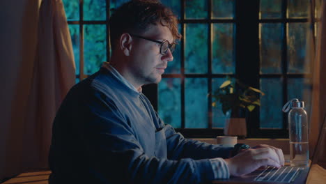 man working on laptop and drinking tea in the evening