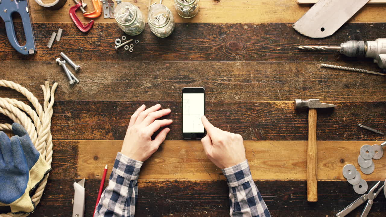 persona que utiliza un teléfono inteligente en un taller