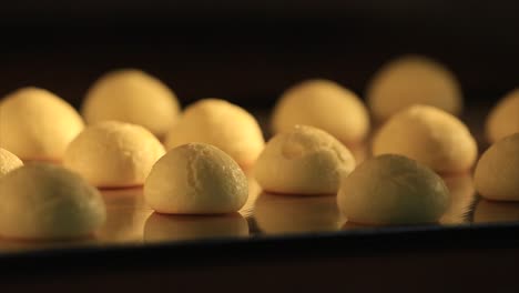 time lapse of making fresh cookies in oven, baking and rising, on black background. front view.