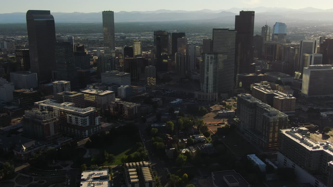 la luz del sol brilla entre edificios altos en la ciudad de denver
