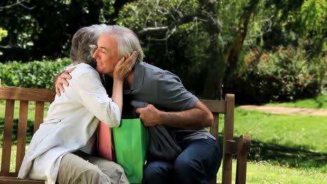 Senior-couple-looking-at-clothes-after-shopping-on-a-bench