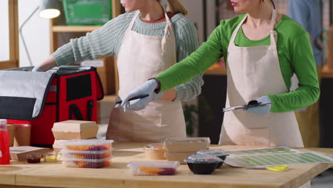 mujeres empacando contenedores de comida para llevar en bolsas de entrega