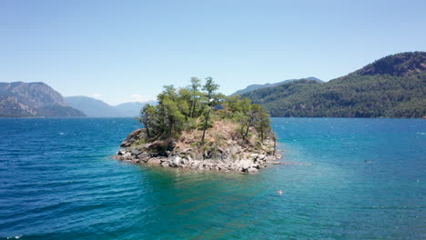 la gente nada en una isla rocosa en un lago junto a las montañas de los andes, se retiran los drones